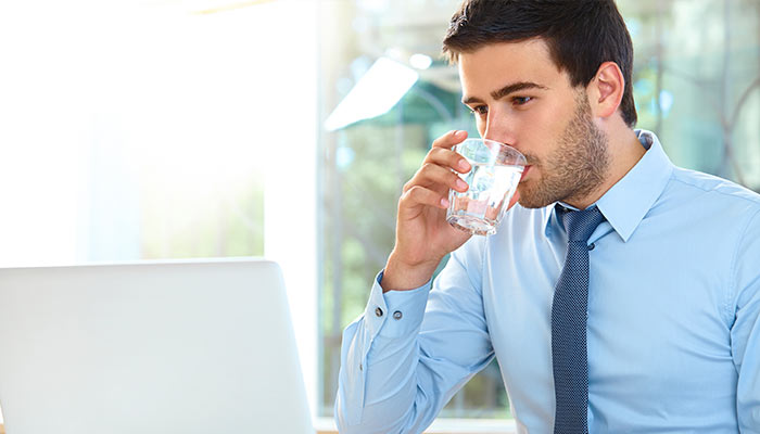 businessman drinking water while on laptop