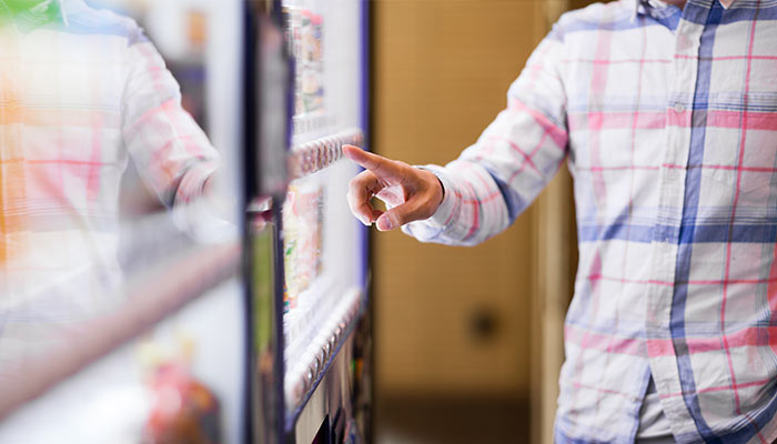 man in plaid shirt pointing at vending machine